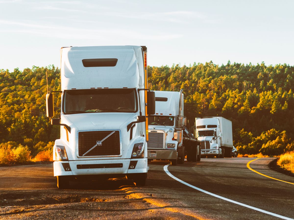 Camions de fret semi-remorques roulant sur une autoroute à l'heure dorée.