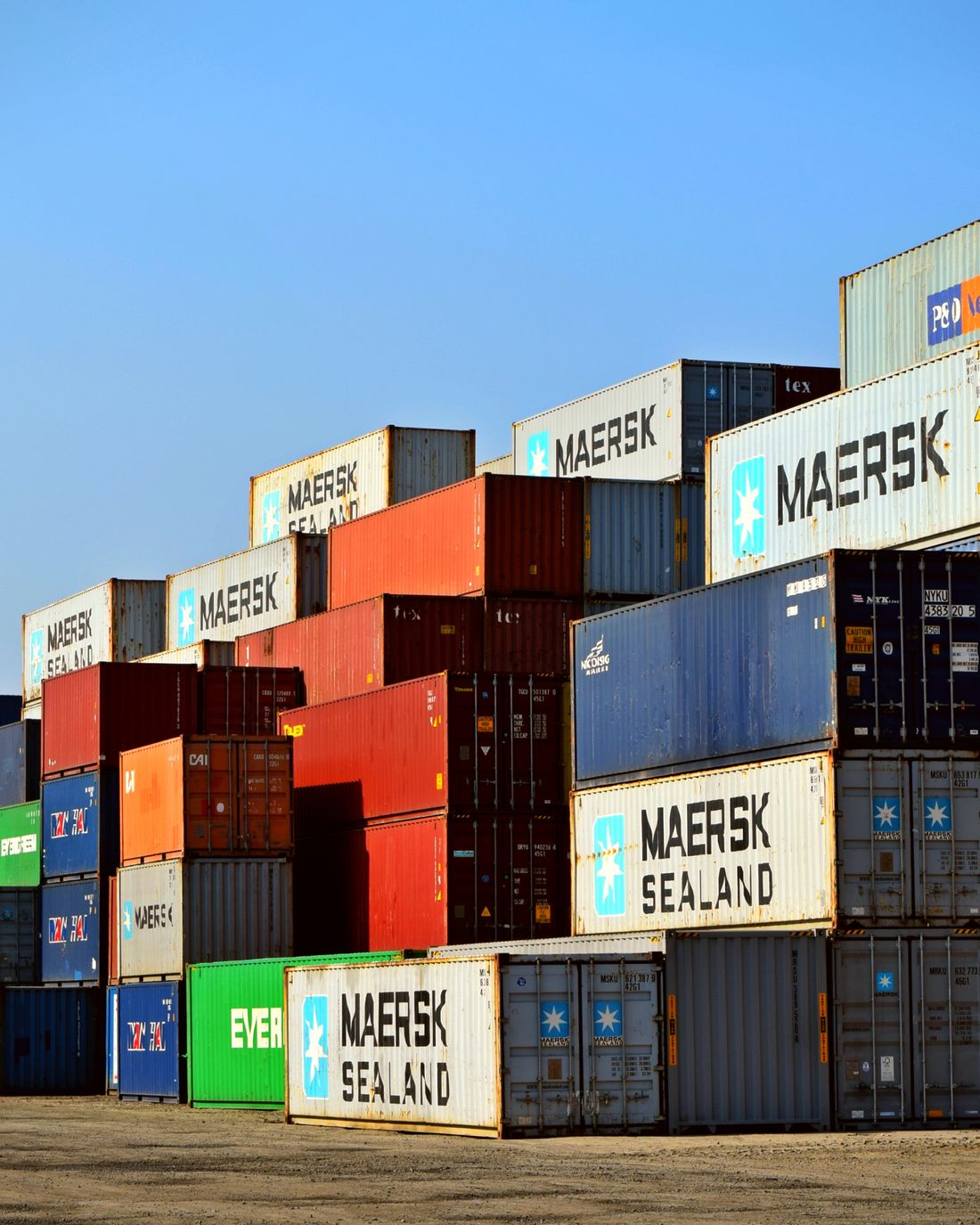 Conteneurs maritimes multicolores empilés sur un terminal portuaire — fret international en transit.
